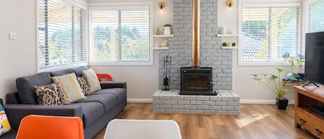 A living room with a fireplace, a sofa, a TV, and a dining area.