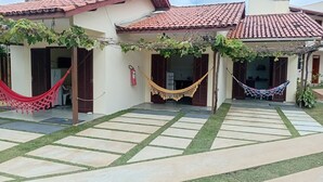 Un patio con techo de tejas, una hamaca y un extintor.