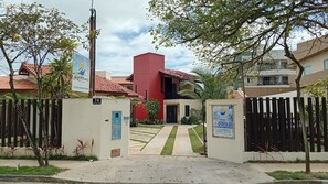 A gated entrance to a residential area with a red building, a blue door, and a sign for 'Solaris do Atlântico'. - Solaris do Atlantico (Ilhéus)
