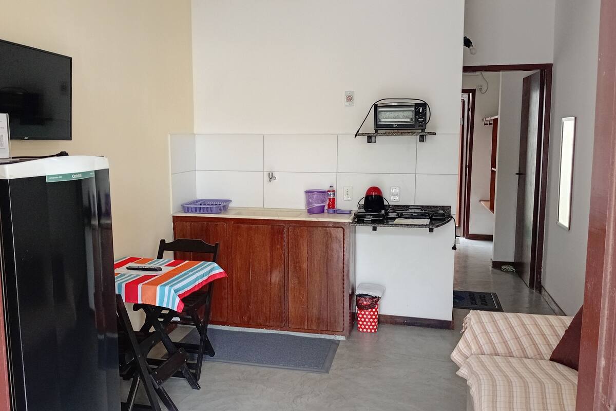 A compact kitchen with a refrigerator, a microwave, a toaster, and a small dining area with a table and chairs.