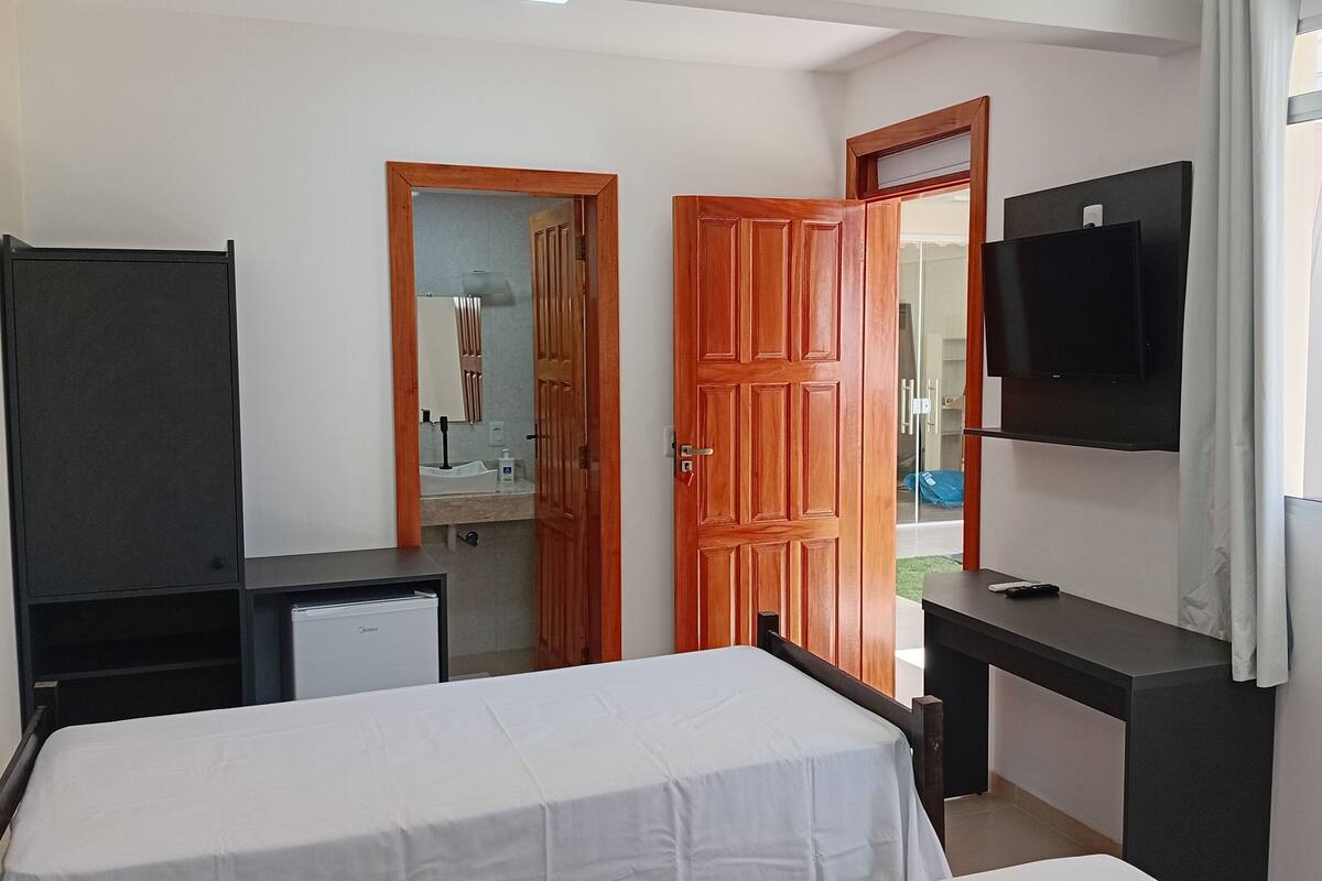 A bedroom with a bed, a desk, a TV, and a wardrobe.