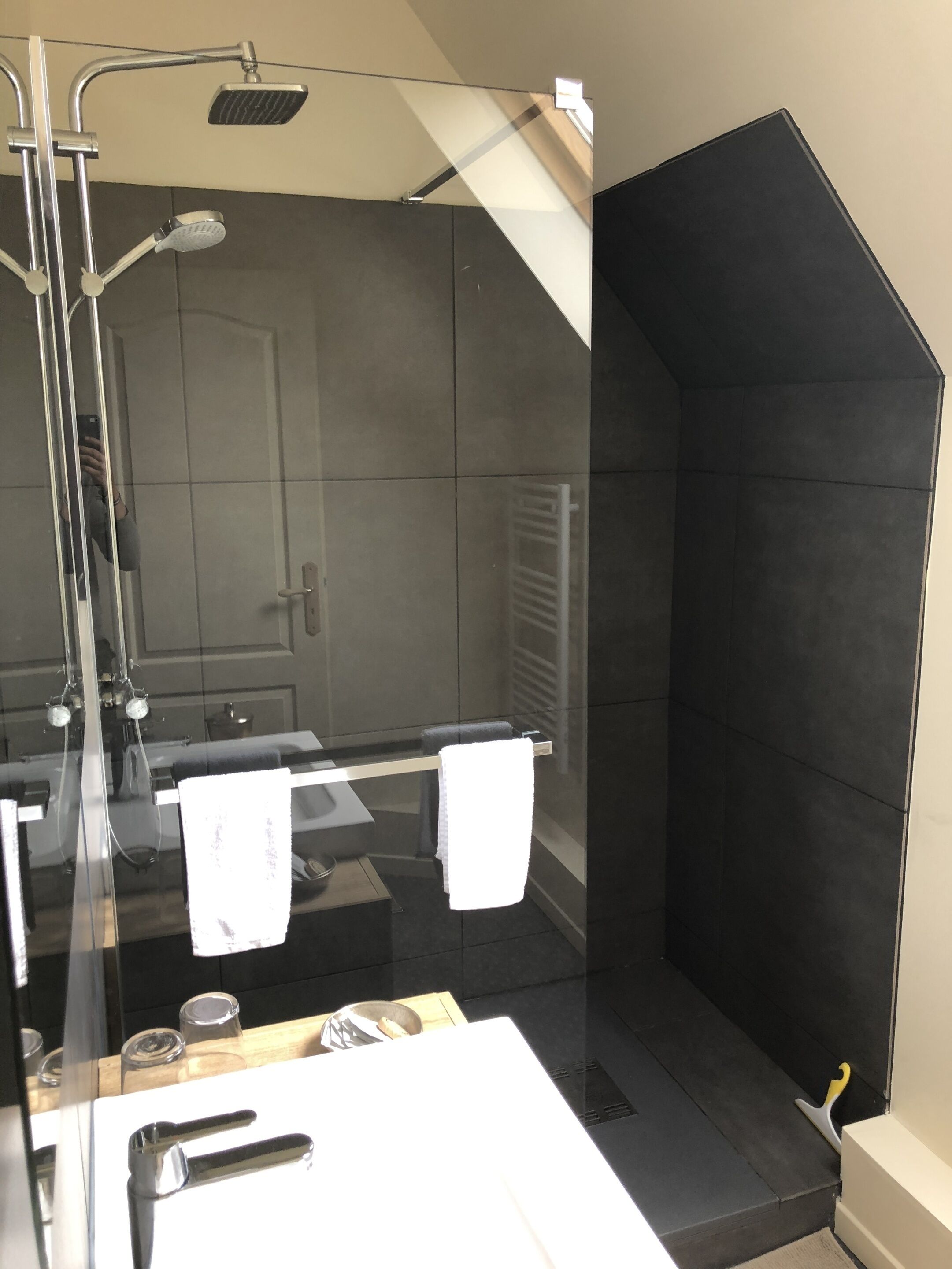 A modern bathroom with a glass-enclosed shower, a white sink, and a towel rack.
