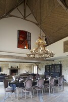 Uma sala de jantar espaçosa com um lustre grande, paredes de pedra e lareira.
