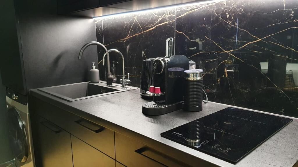 A modern kitchen with a built-in sink, a coffee maker, and an induction cooktop.