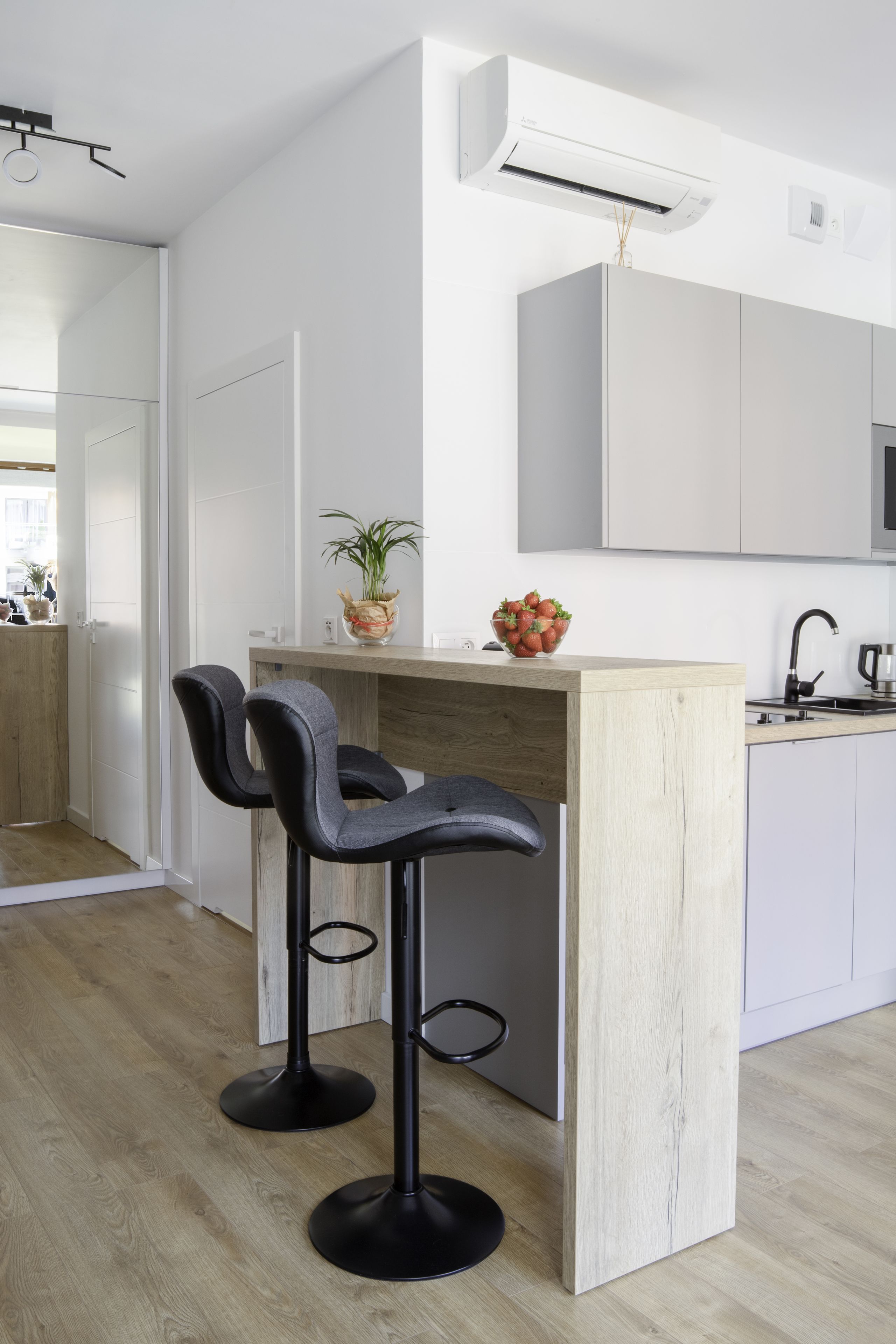 Una cocina moderna con dos taburetes de bar, una isla de madera y una encimera blanca.