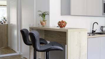 Una cocina moderna con dos taburetes de bar, una isla de madera y una encimera blanca.