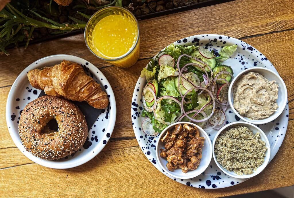 A plate with croissants, a salad, and various dips on a wooden table.