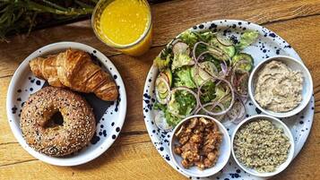 A plate with croissants, a salad, and various dips on a wooden table.