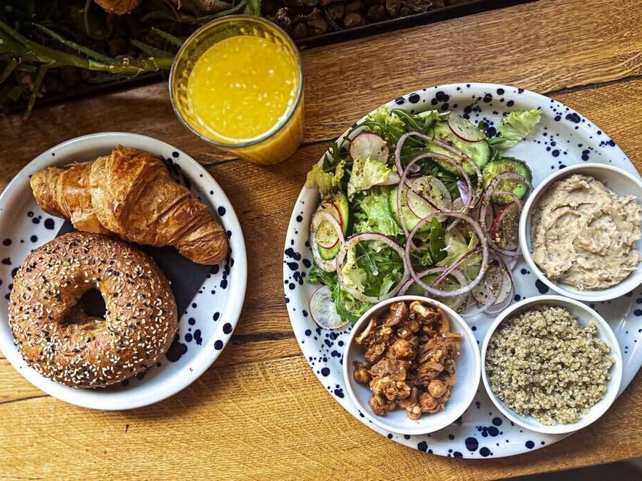 A plate with croissants, a salad, and various dips on a wooden table.