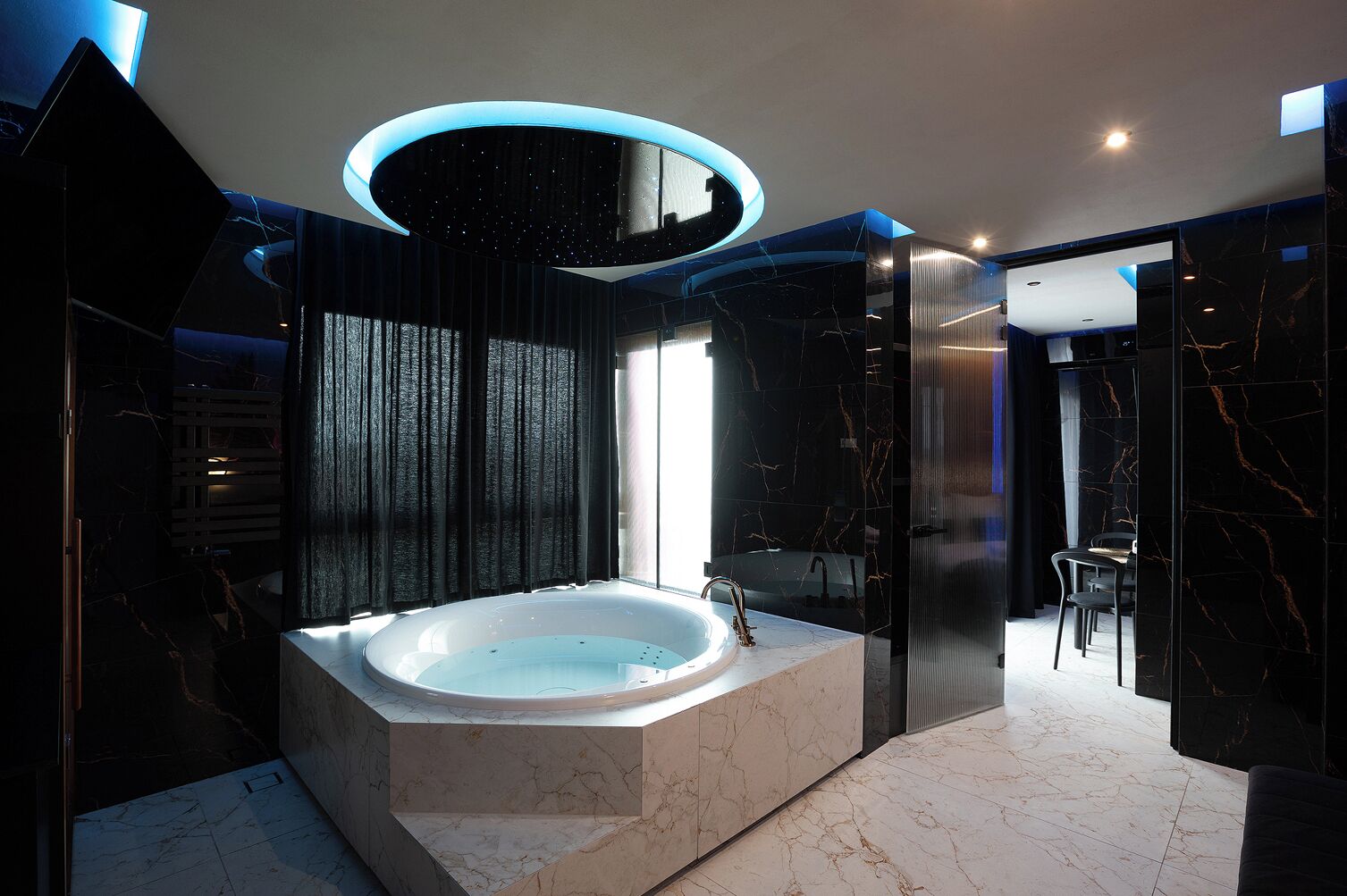 A modern bathroom with a freestanding bathtub, dark marble walls, and a circular skylight.