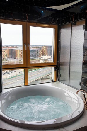 A hot tub with a city view through large windows.