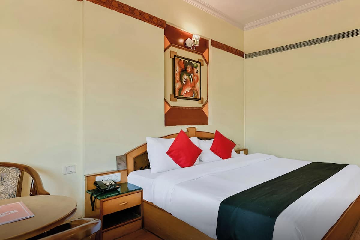Een hotelkamer met een bed, een bureau met telefoon, een stoel en een deur.