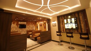 Ein Restaurant mit Sitzboxen und hohen Hockern, einer Holzbalkendecke und einem an der Wand befestigten Fernseher.