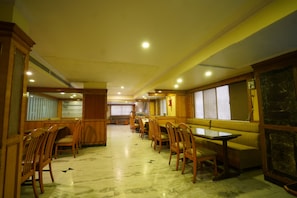 Un espace repas avec des meubles en bois, un sol en marbre et un mur décoratif en pierre.
