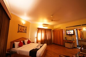Une chambre d’hôtel avec un lit, un bureau, une télévision et un miroir.