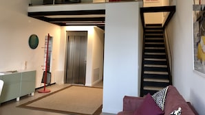 A two-story apartment with a staircase, a sofa, a desk, and a coat rack. - Rivadige Suite (Verona)