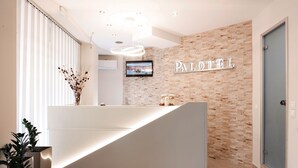 A hotel reception area with a modern design, featuring a reception desk, a wall-mounted TV, and a sign that reads "PALOTEL". - Palotel Design Gouvia (Corfu)
