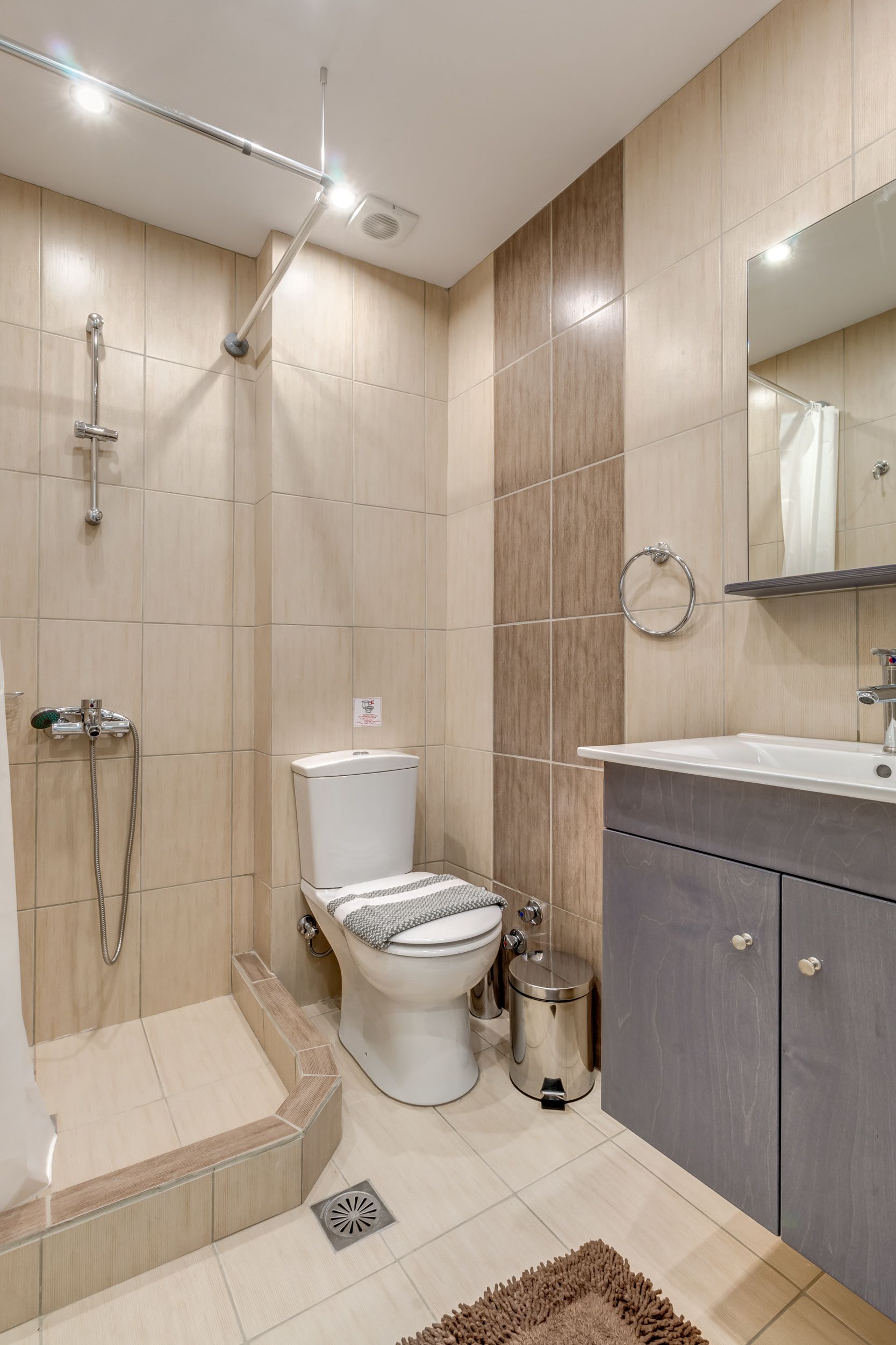 A modern bathroom with a shower, toilet, and sink.