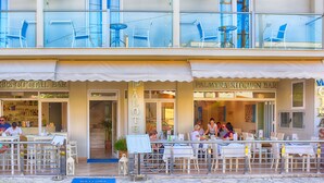 A restaurant with outdoor seating, a bar, and a kitchen bar. - Palotel Design Gouvia (Corfu)