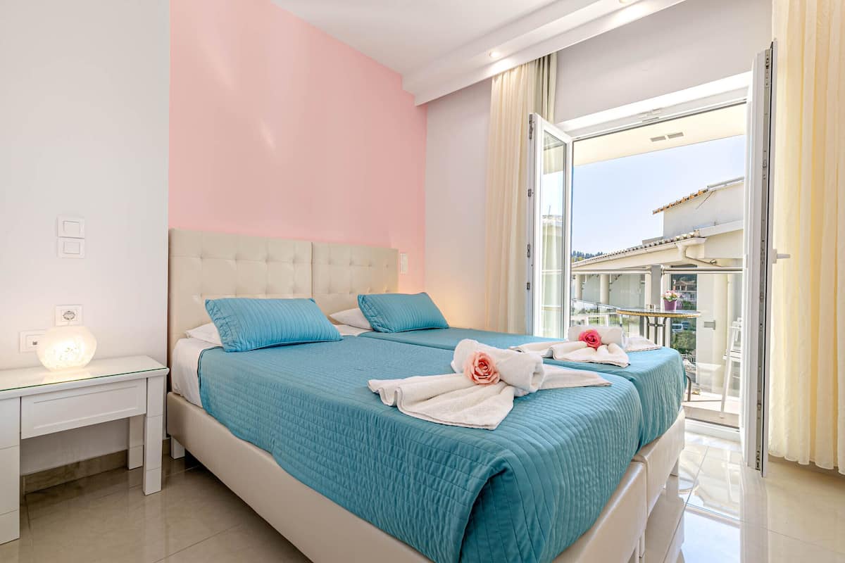 A hotel room with a large bed, a nightstand, and a view of the outside balcony.
