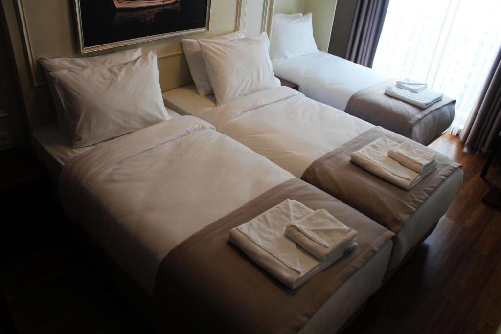 Une chambre d’hôtel avec deux lits, chacun étant équipé de draps blancs et de serviettes pliées.