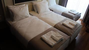 Une chambre d’hôtel avec deux lits, chacun étant équipé de draps blancs et de serviettes pliées.