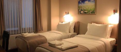 A hotel room with two beds, a window with curtains, a painting on the wall, and bedside lamps.