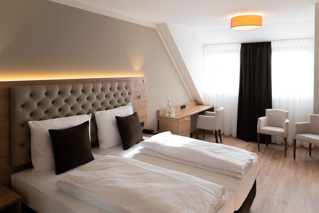 Une chambre d’hôtel avec un grand lit, un bureau et deux chaises.