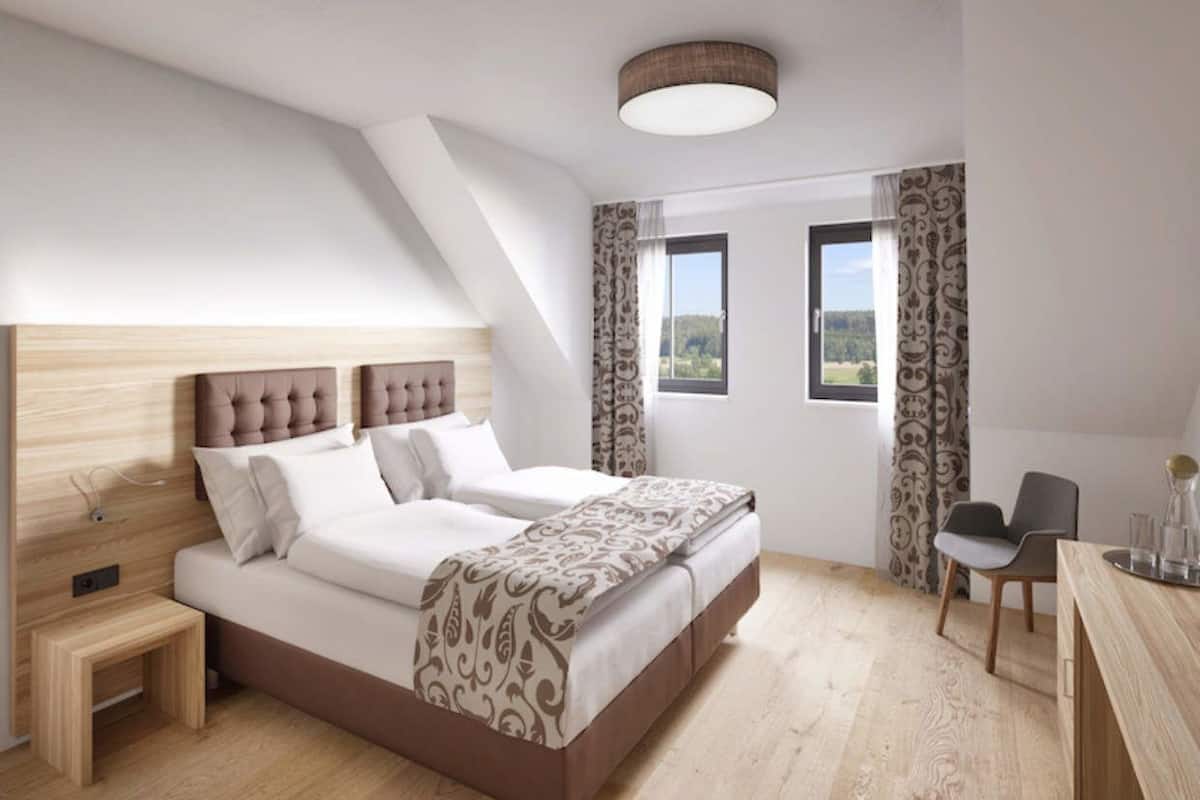 A bedroom with a bed, bedside tables, a desk, and a chair.
