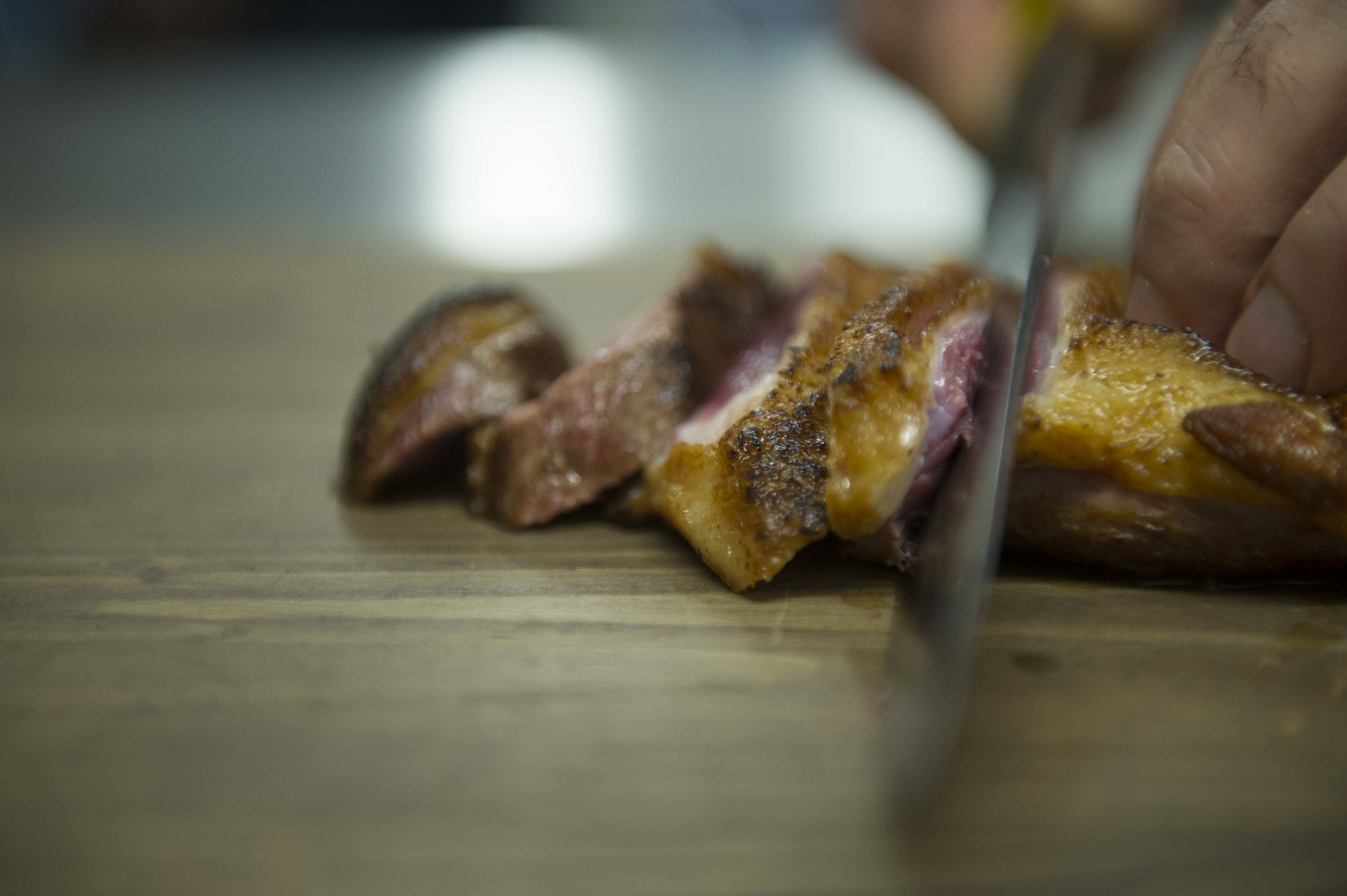 A close-up of a steak being sliced on a wooden cutting board.