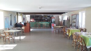 A spacious room with multiple tables and chairs, a bar area with shelves of bottles, and a map on the wall. - Camping Europa Beach (Sorbo-Ocagnano)