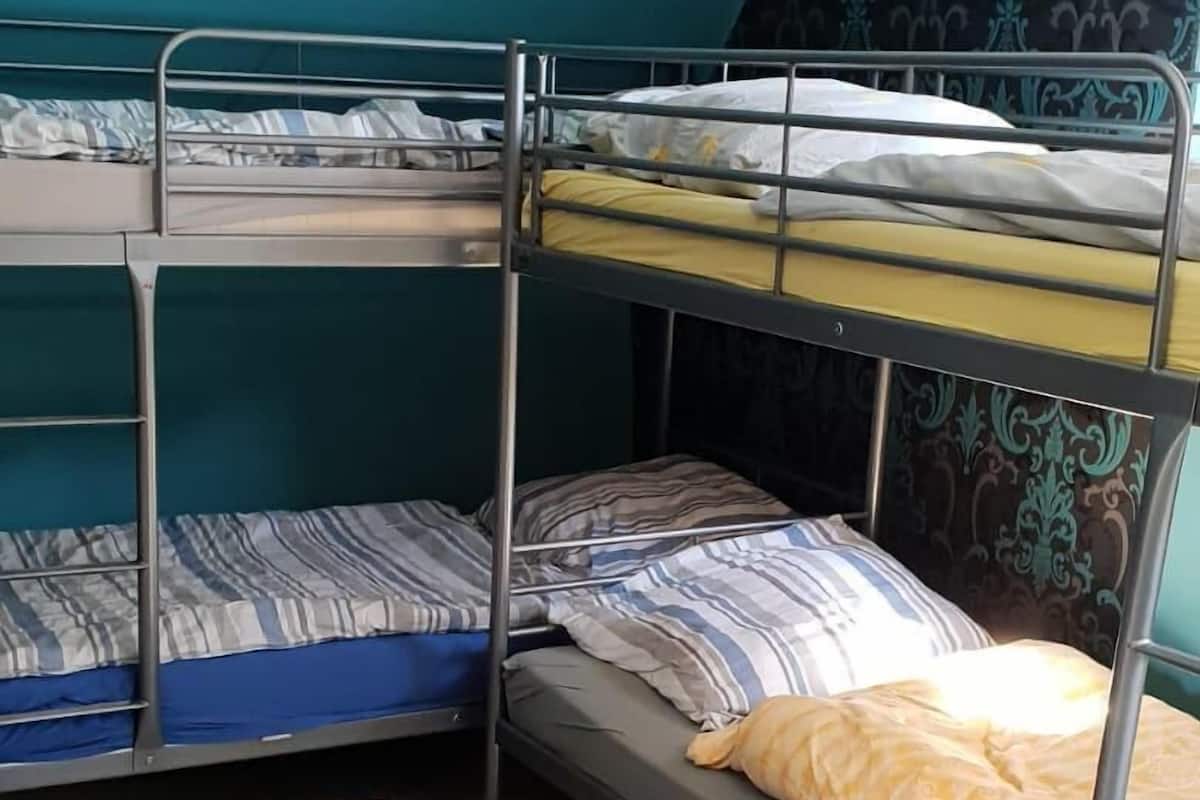 A dormitory room with bunk beds, a small table, and a patterned wall.