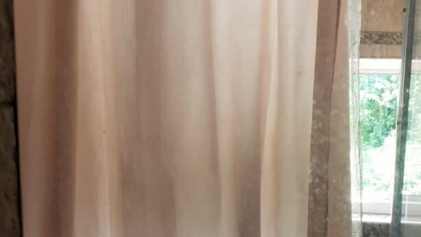 A bathroom with a shower curtain, a glass door, and a tiled floor.