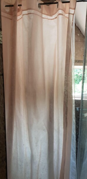 A bathroom with a shower curtain, a glass door, and a tiled floor. - Pension Römer (Lampertheim)