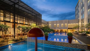A modern hotel with a swimming pool, outdoor seating, and a well-lit facade. - Radisson Lampung Kedaton (Bandar Lampung)