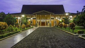 A large building with a prominent entrance, a paved walkway leading to it, and well-maintained landscaping. - Radisson Lampung Kedaton (Bandar Lampung)