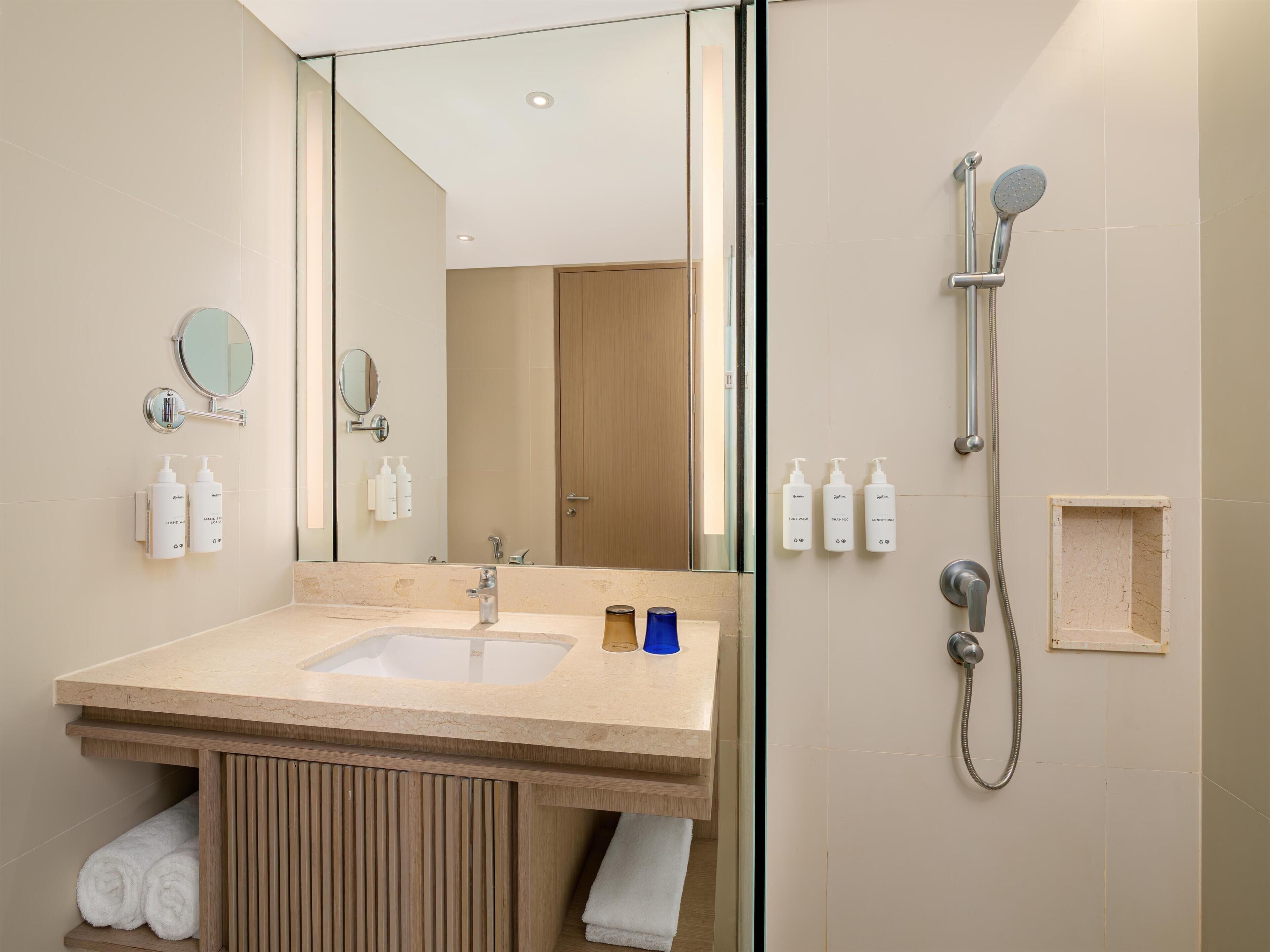 A modern bathroom with a sink, mirror, and shower.