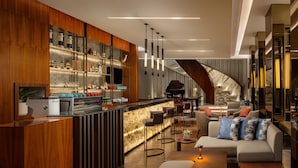A modern bar area with a wooden bar counter, seating, and a piano. - Radisson Lampung Kedaton (Bandar Lampung)