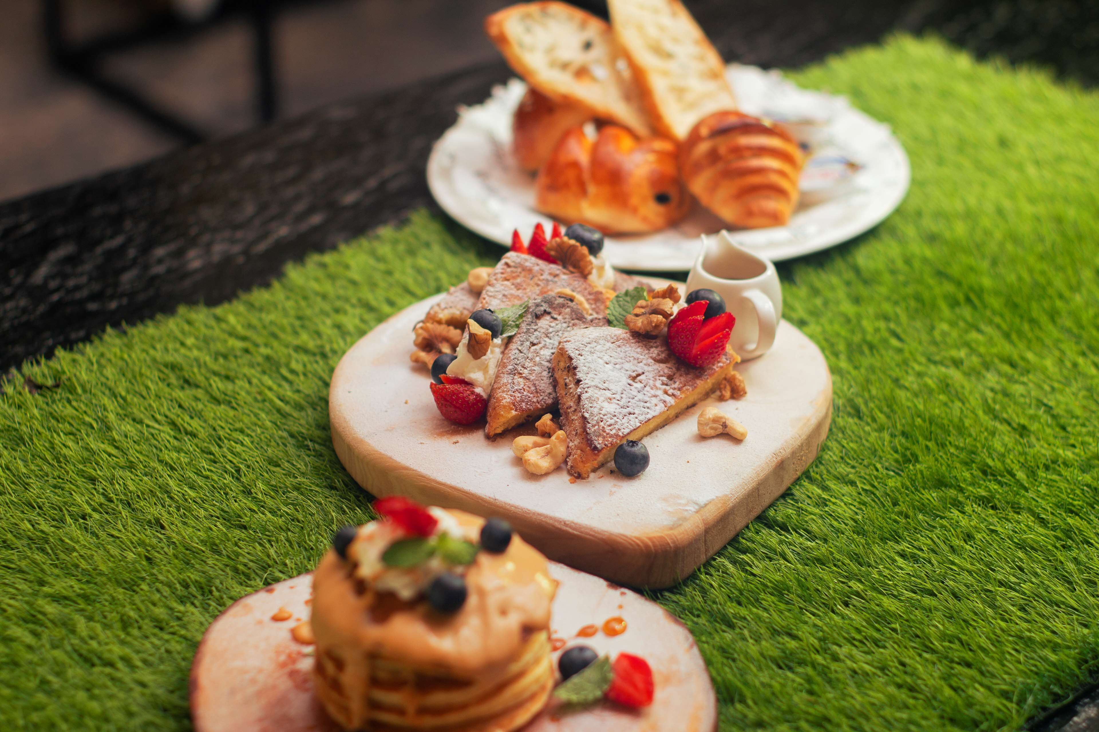 A breakfast setting with waffles, pastries, and a cup of coffee on a green surface.