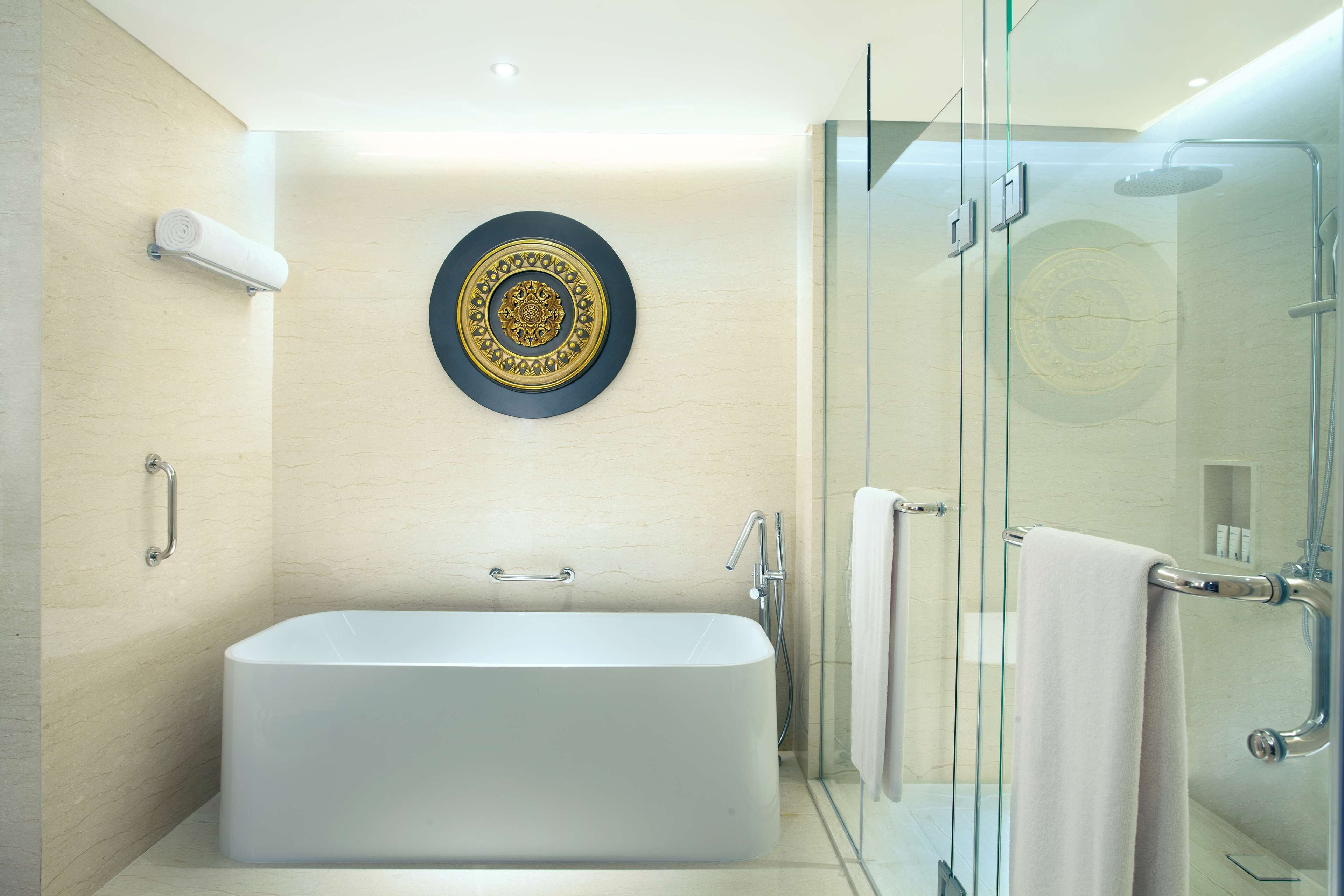 A modern bathroom with a freestanding bathtub, glass shower enclosure, and a decorative wall plate.