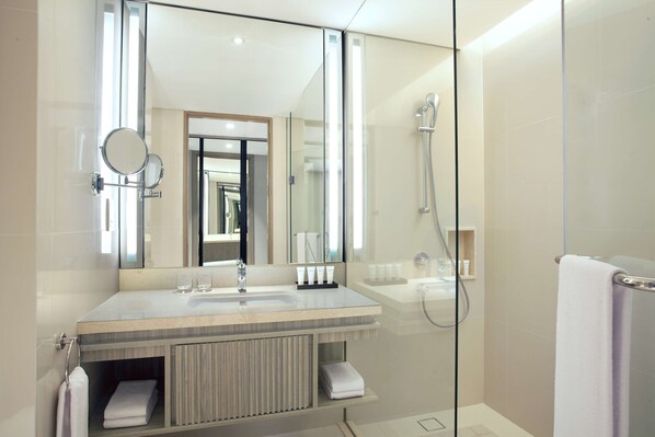 A modern bathroom with a glass-enclosed shower, a large mirror, and a vanity with a sink and towel rack.