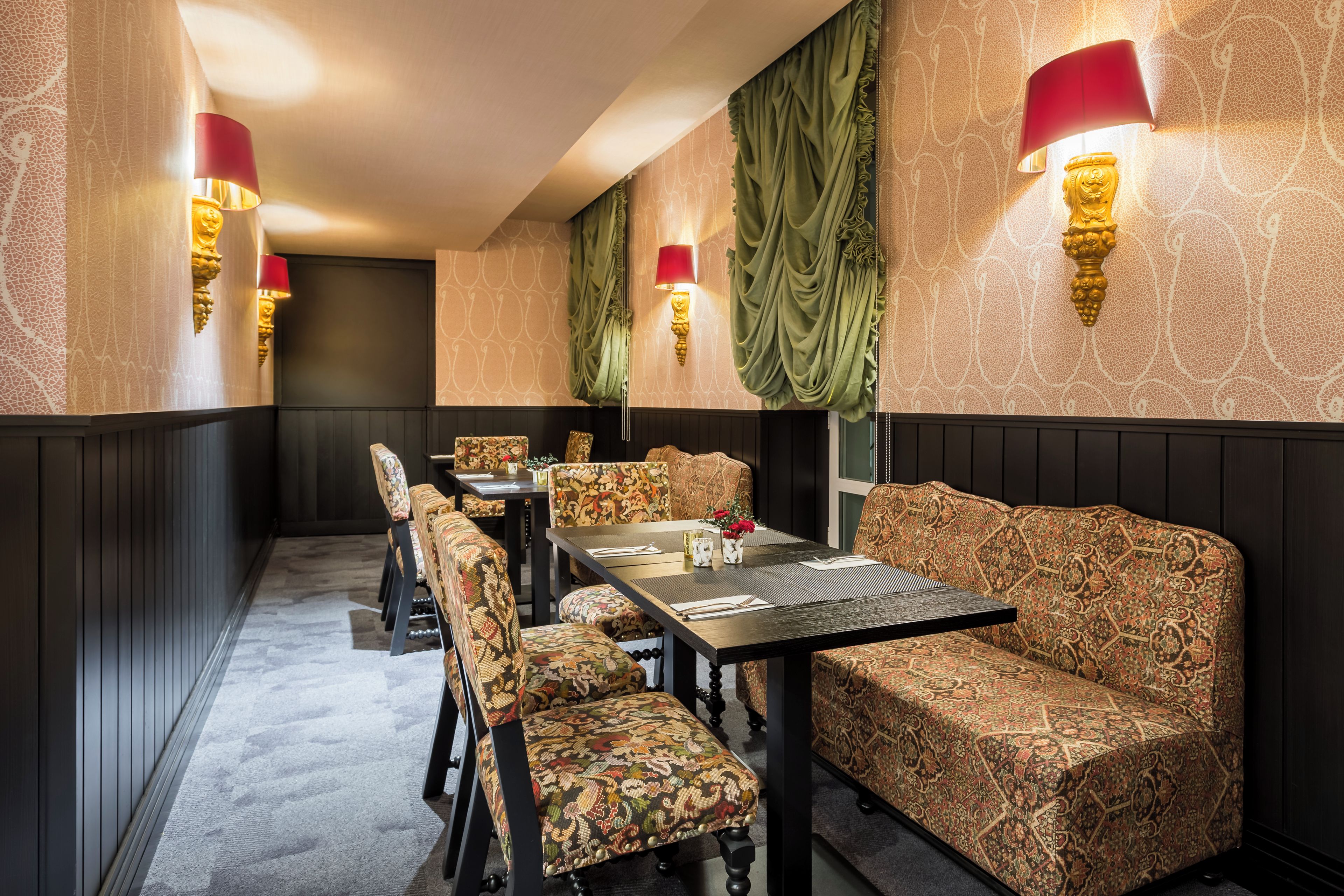 Een eetruimte met gestreept bekleden meubilair, een donker houten tafel en wandlampen.