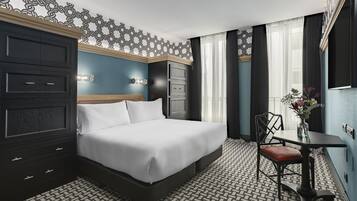 Habitación de hotel con una cama grande, un escritorio con una silla, una pared decorativa y un suelo estampado.