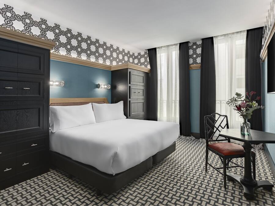 Habitación de hotel con una cama grande, un escritorio con una silla, una pared decorativa y un suelo estampado.