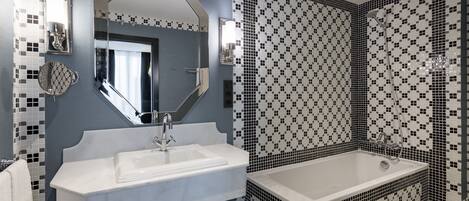 A bathroom with a white sink, a large mirror, and a black and white patterned shower area.