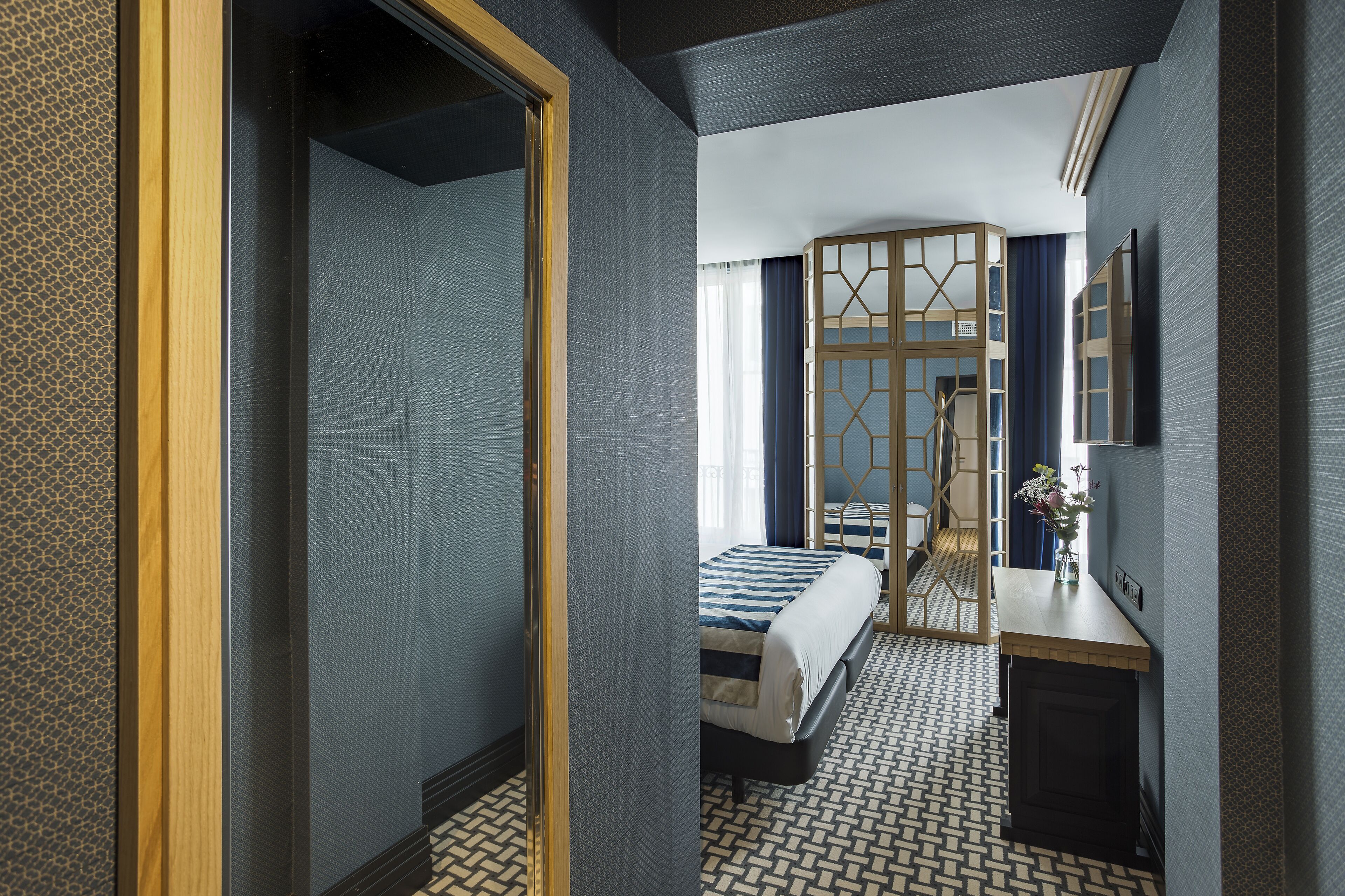 Una habitación de hotel con una cama, un escritorio y un espejo.