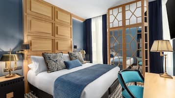 Una habitación de hotel moderna con una cama grande, un armario de madera, un escritorio y una silla.