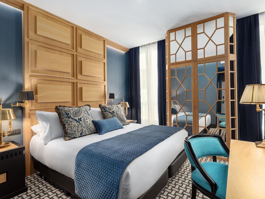 Una habitación de hotel moderna con una cama grande, un armario de madera, un escritorio y una silla.