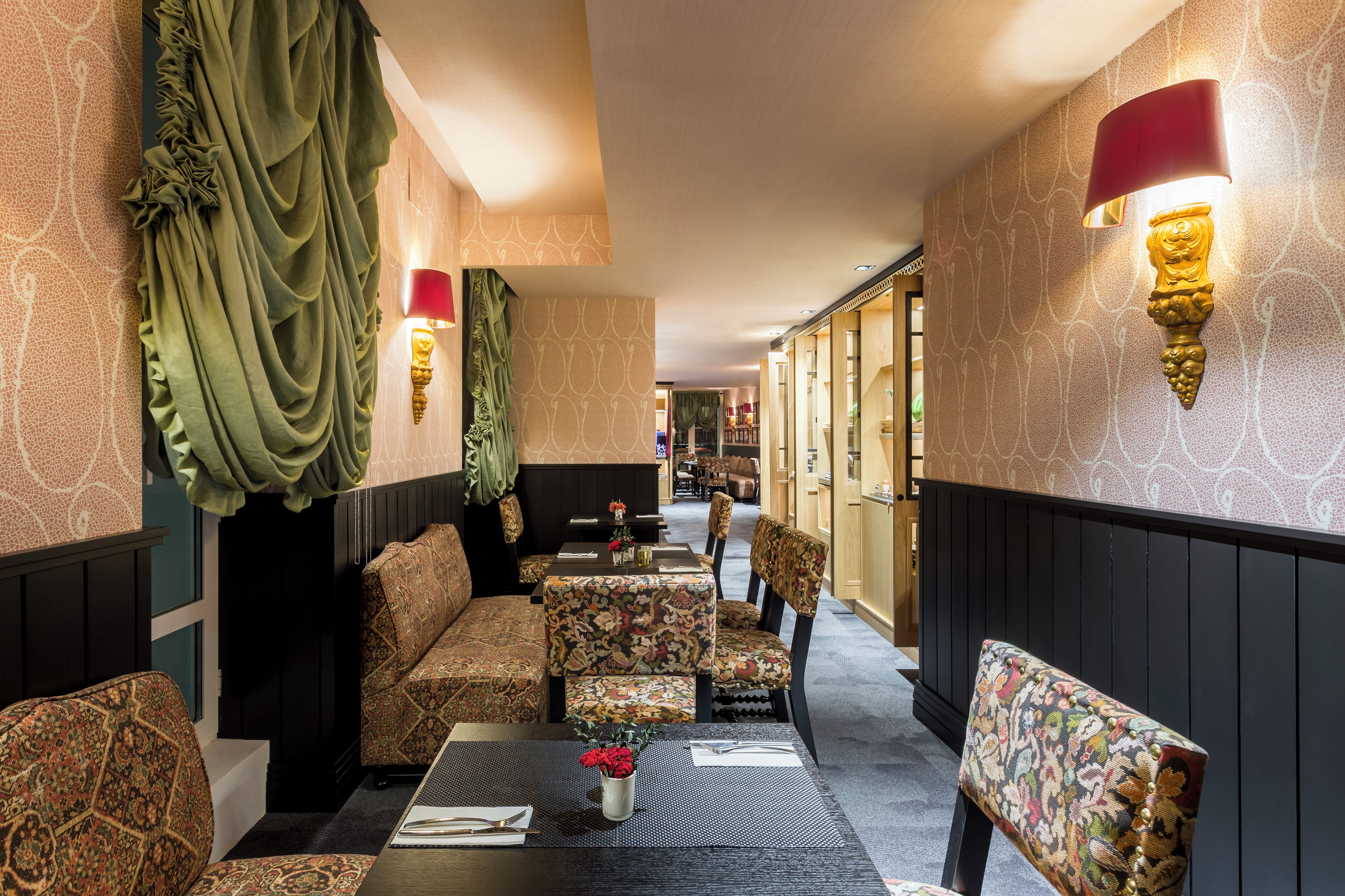 A corridor with patterned walls, seating areas, and wall-mounted lighting fixtures.