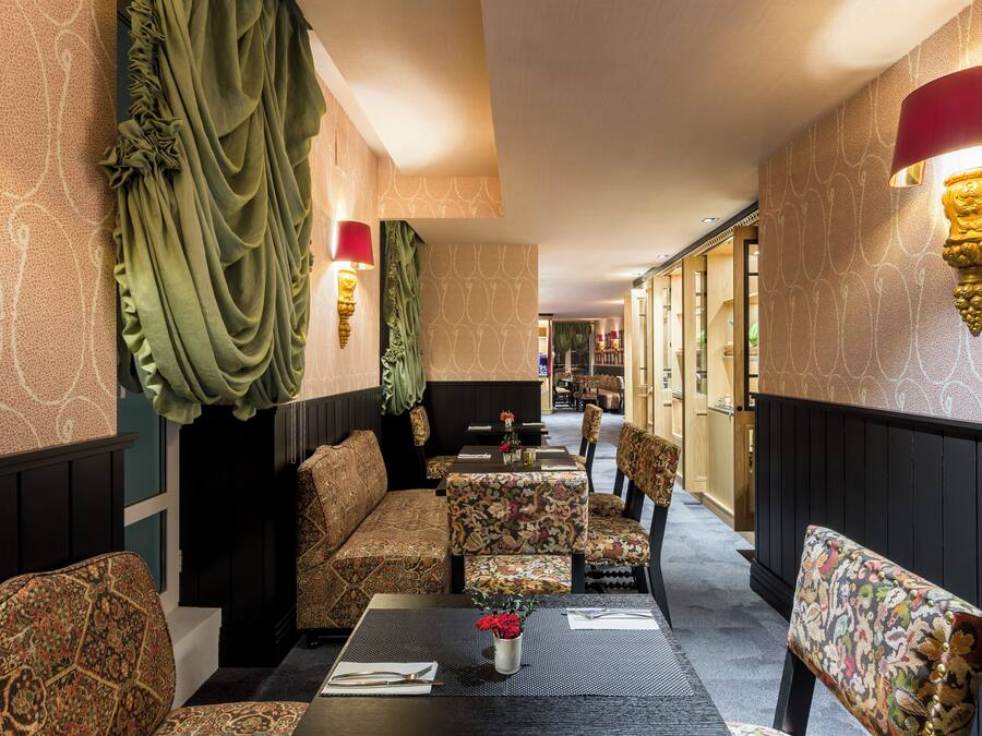 A corridor with patterned walls, seating areas, and wall-mounted lighting fixtures.